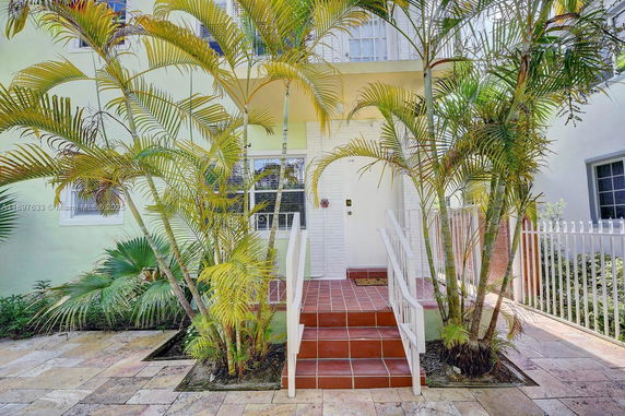 Front view of a house with a tiled entrance and surrounding palm plants.