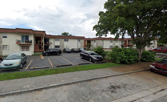 Front view of a residential building with a parking area in front.