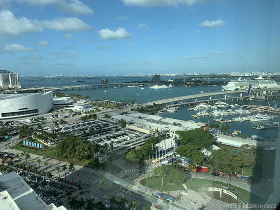 Wide angle view of a harbor area with ships and a city skyline in the distance.