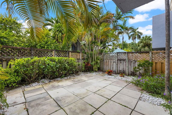 Paved patio area with surrounding plants and a wooden fence.