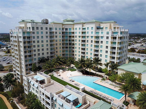 Front view of a multi-story condominium complex with a swimming pool area.