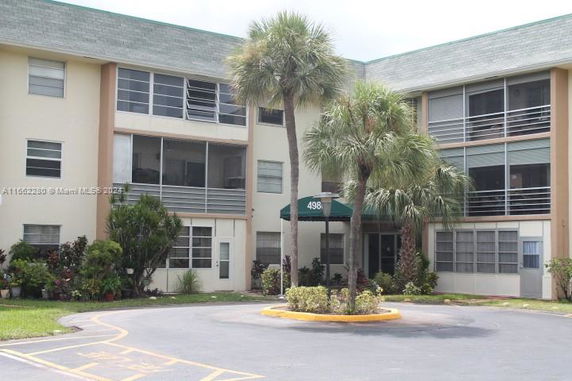 Front view of a multi-story building with a flat roof and balconies.