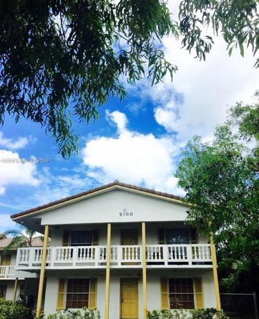 Front view of a two-story house with a balcony and brown roof.