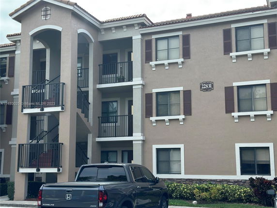 Front view of a multi-story residential building with balconies and a parked truck.
