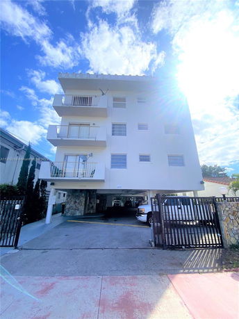 Front view of a multi-story apartment building with outdoor parking underneath.