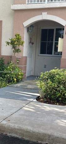 Front entrance of a house with an arched doorway and window beside it.