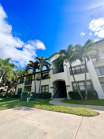 Front view of a two-story apartment building with balconies and a stairwell.