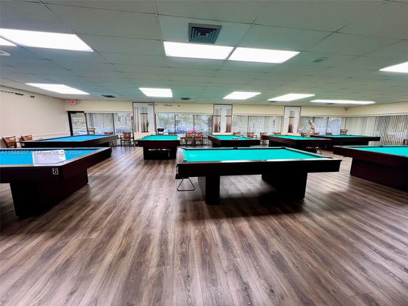 Room with multiple billiards tables and wood flooring.