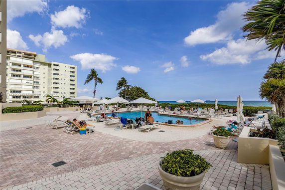 Outdoor swimming pool area with lounge chairs and umbrellas.