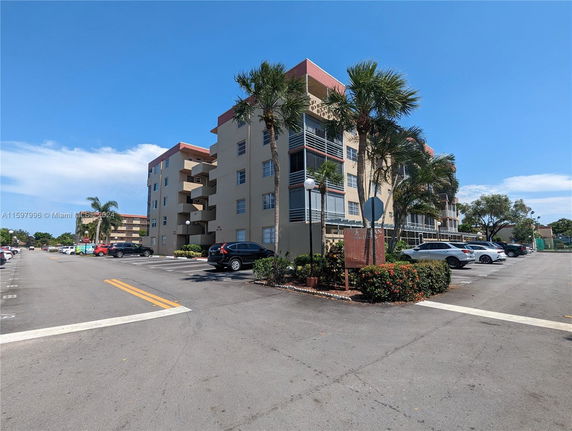 Multi-story residential building with adjacent outdoor parking area.