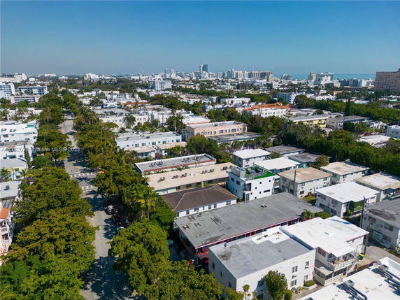Aerial view of a cityscape with multiple residential and commercial buildings surrounded by trees.