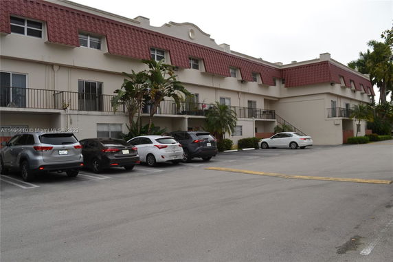 Parking area in front of a multi-story building with red-tiled accents.