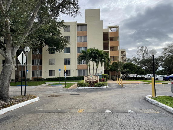 Front view of a multi-story apartment building with a sign indicating 'Palm Court at Coral Springs'.