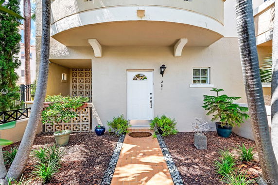 Front view of a house with a covered entryway and decorative block wall.