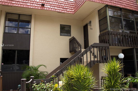 Front view of a two-story building with external staircase and balcony.