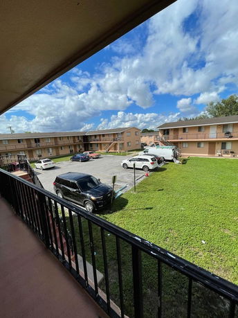 View of apartment buildings with a parking area and green lawn.