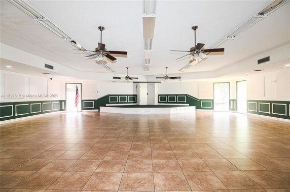 Interior view of a spacious room with ceiling fans and a stage.