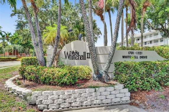 Front view of a residential building with a sign reading 'Whitehall II' and address '1701-1721 Whitehall Drive'.