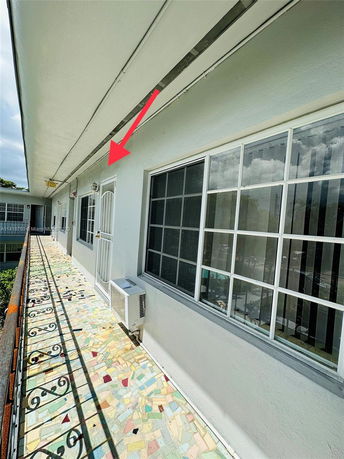 Exterior corridor of a building with a decorative floor and metal railing.