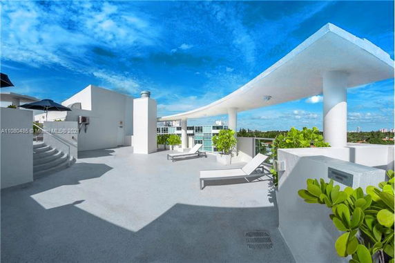 Rooftop with lounge chairs, plants, and a modern architectural canopy.