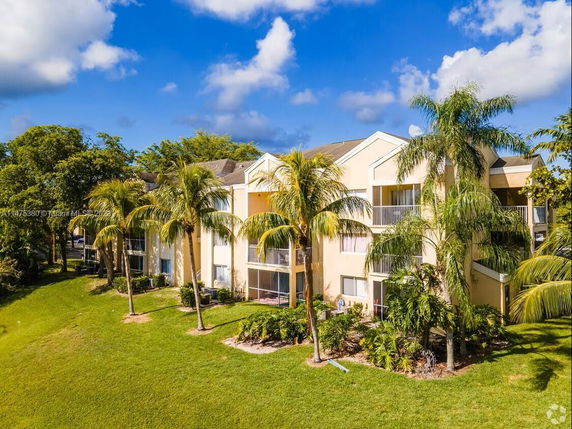Front view of an apartment building with multiple balconies and palm trees.