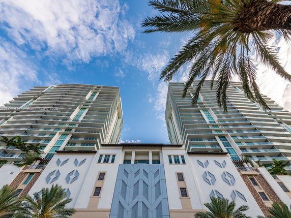 View looking up at a modern multi-story residential building with balconies.