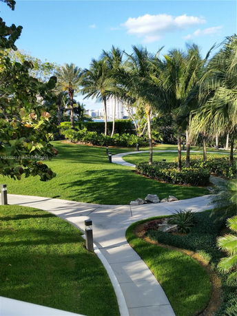 View of surrounding area with palm trees and a walkway leading through a landscaped garden.
