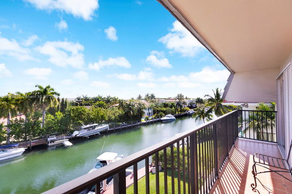 View from a balcony overlooking a canal with boats and surrounding greenery.