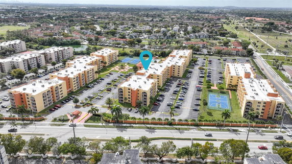 Aerial view of a residential complex with multiple buildings, parking lots, and a basketball court.