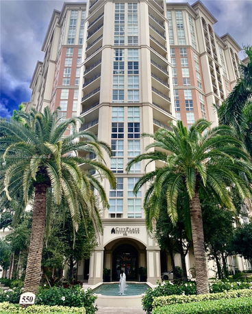 Front view of a tall residential building with multiple balconies and large windows.