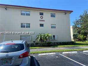 Front view of a three-story apartment building with a parking area in front.