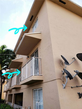 Front view of a multi-story building with balconies and satellite dishes.