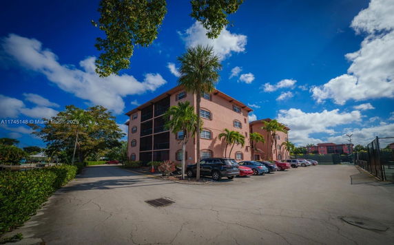 Front view of a multi-story residential building with parked cars in front.