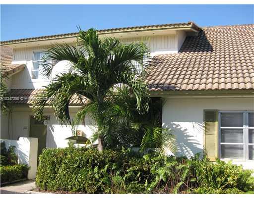Front view of a two-story house with a tiled roof and surrounding greenery.
