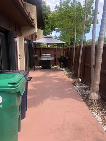 Outdoor area with a grill and trash bins adjacent to a building.