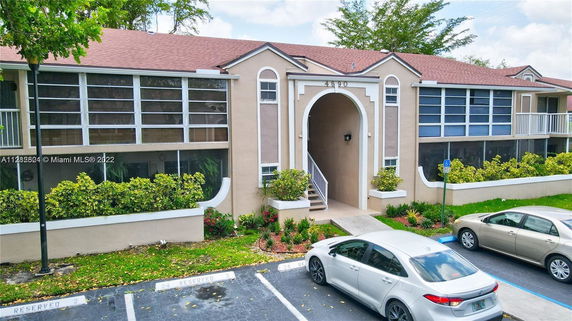 Front view of a two-story building with arched entrance and screened windows.