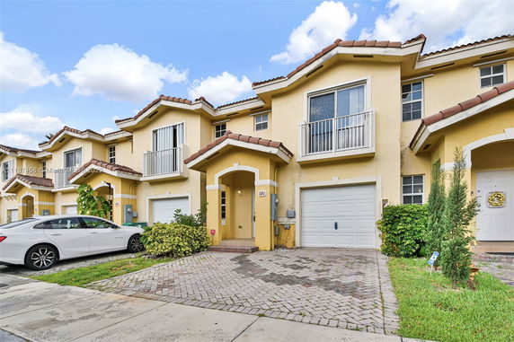 Front view of a two-story townhouse with a garage and a driveway.
