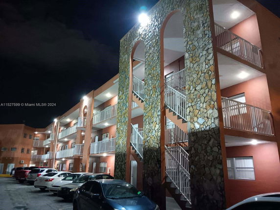 Front view of a multi-story building with parking area at night.