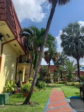 Front view of a multi-story building with palm trees and a walkway.