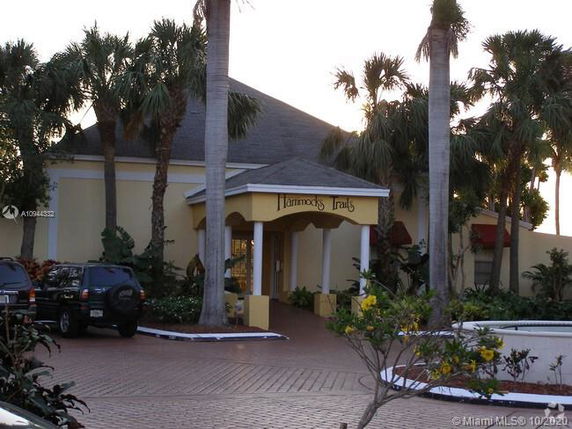 Front view of a building with palm trees and a covered entrance.