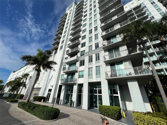 Front view of a tall residential building with multiple balconies.