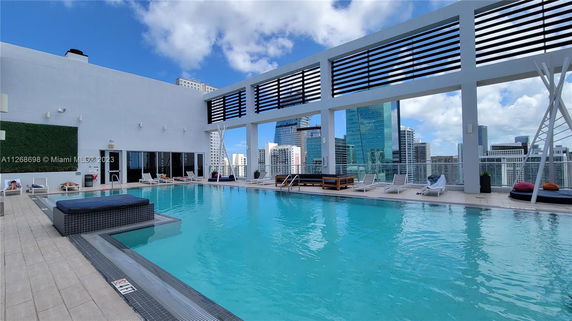 Outdoor rooftop swimming pool area with surrounding lounge chairs and city skyline view.