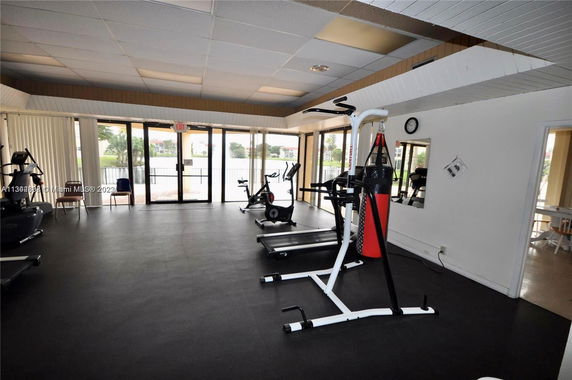 Indoor gym area with exercise equipment and large windows.