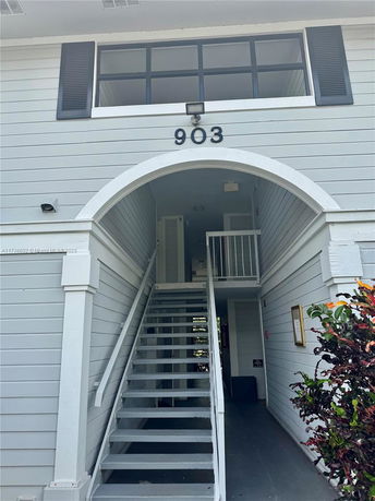 Front view of a house with an arched entry and stairs leading to the second floor.