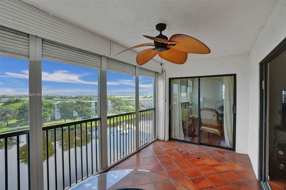 View of surrounding areas from a balcony with sliding glass doors and a ceiling fan.