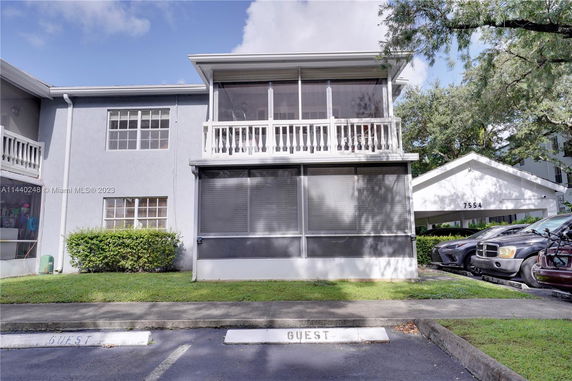 Front view of a two-story building with a screened porch and balcony.