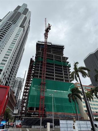 Front view of a high-rise building under construction with a crane.