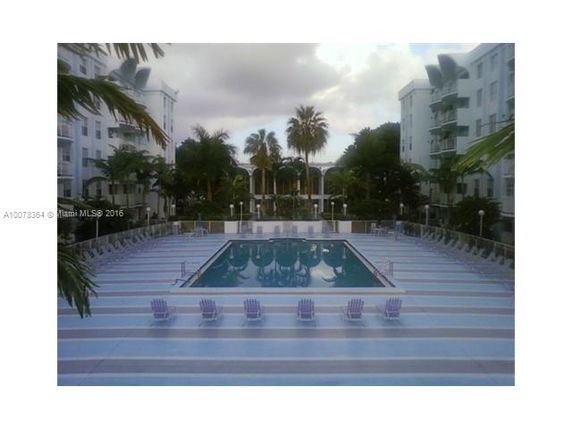 Outdoor swimming pool area with surrounding chairs and tall buildings.