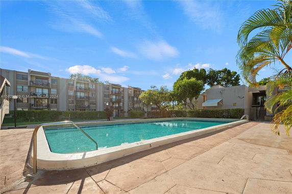 Outdoor swimming pool area with apartment buildings in the background.