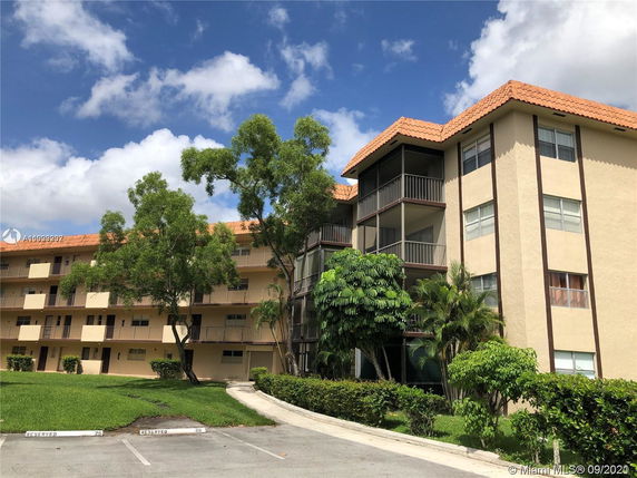 Front view of a multi-story residential building with balconies and a tiled roof.